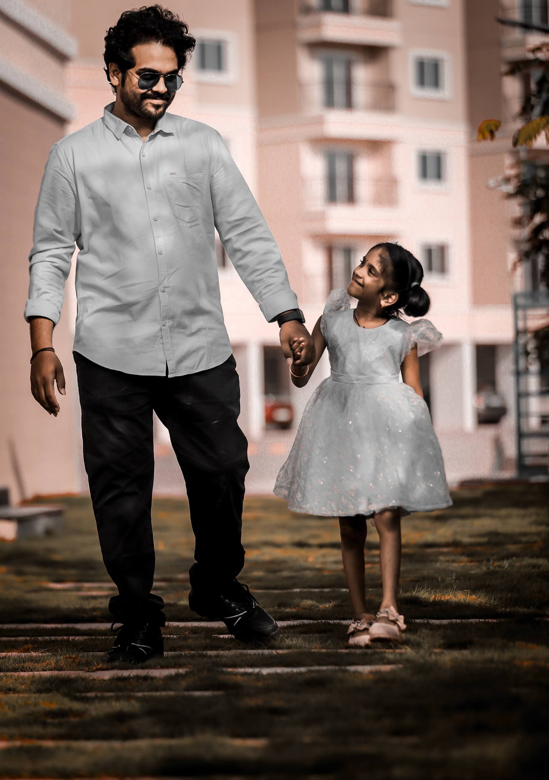 Father in casual shirt walking with young daughter in white dress