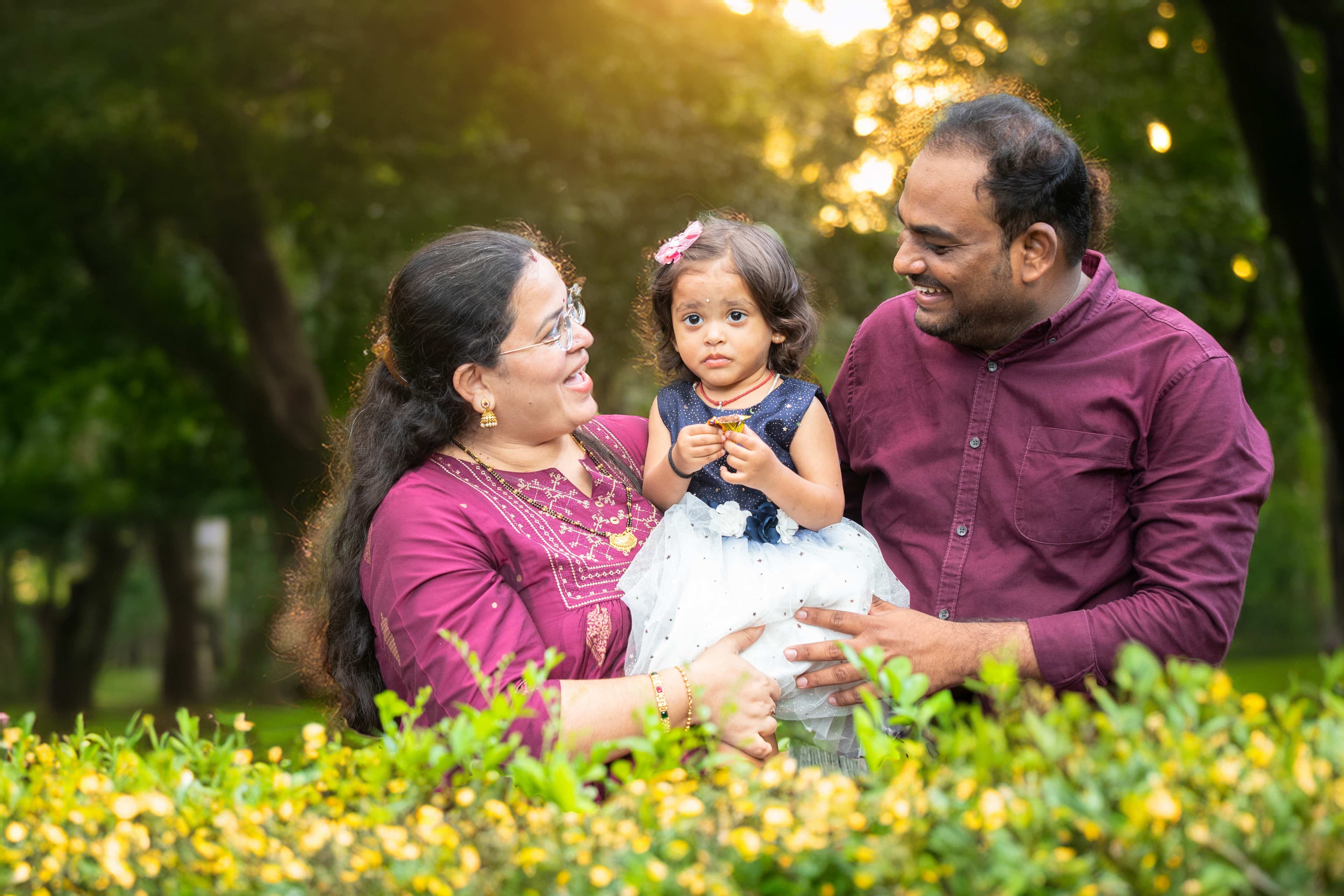 Family with young daughter in garden during golden hour sunset