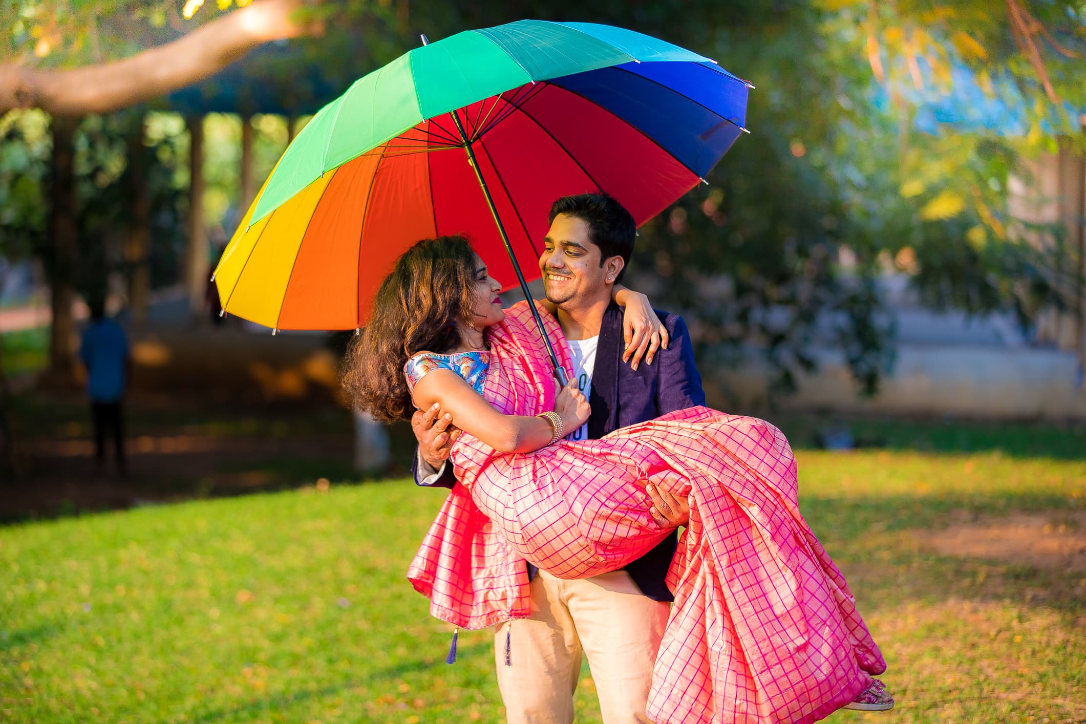 Couple under colorful rainbow umbrella in garden setting