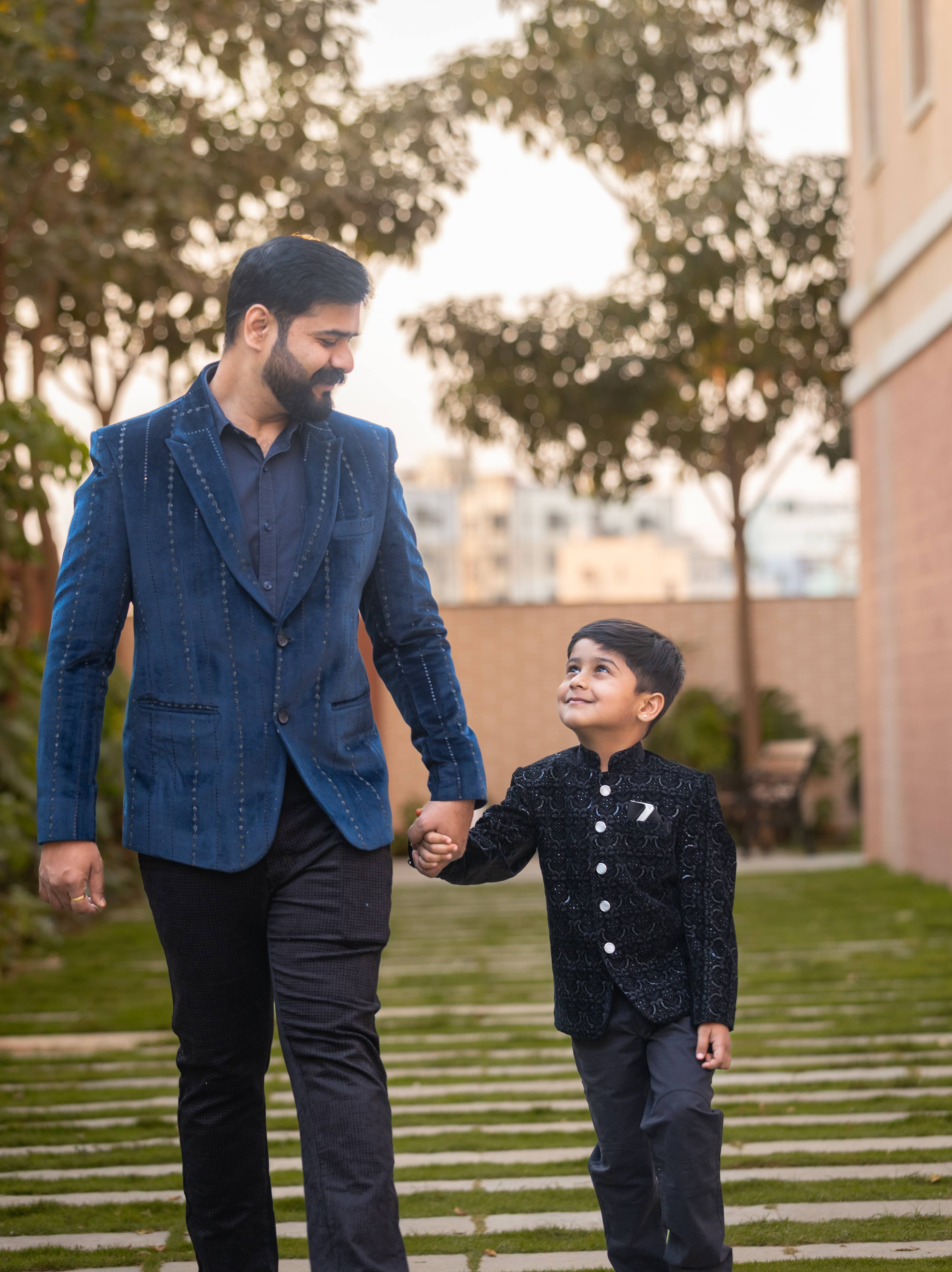 Father and son walking hand in hand in elegant formal suits